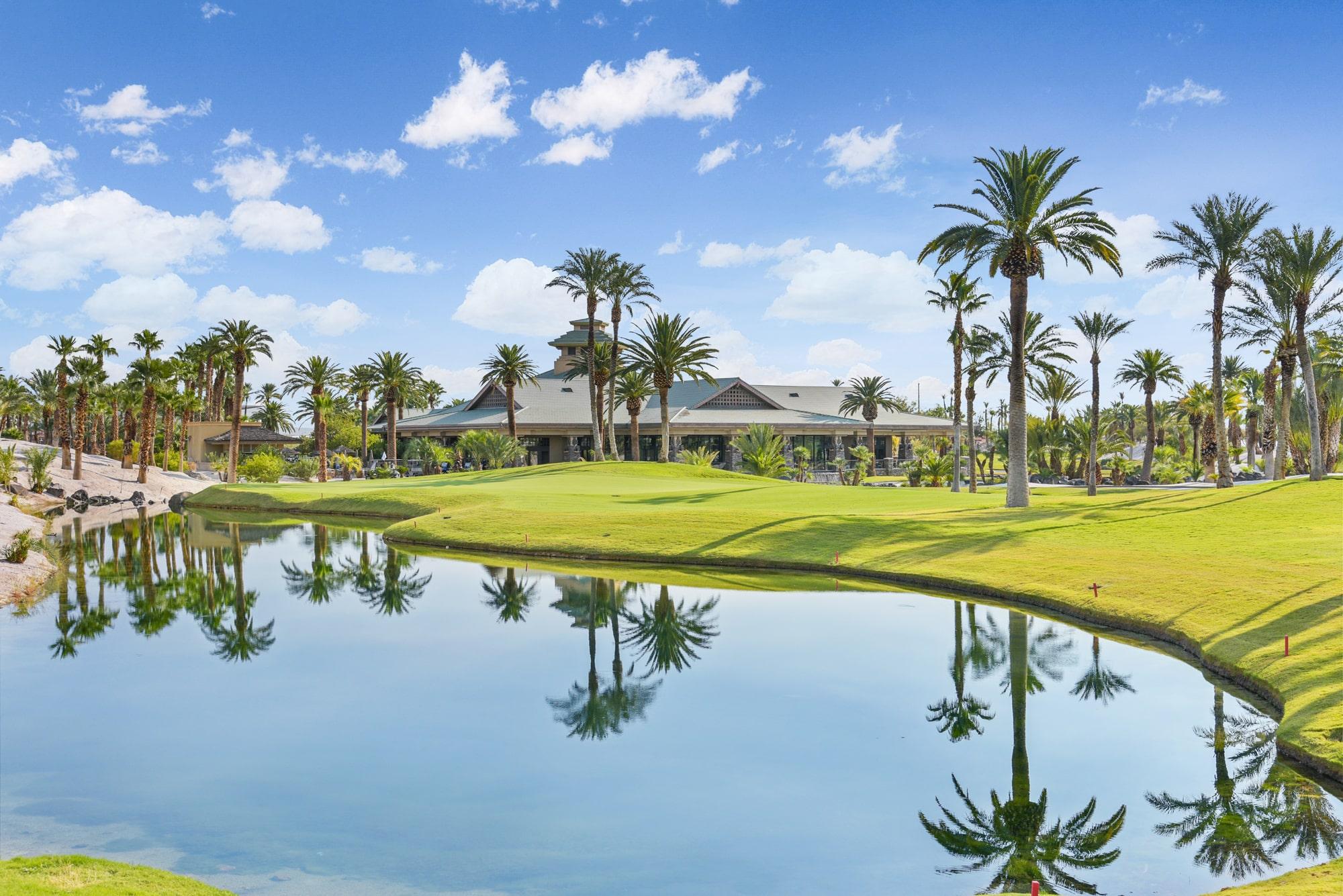 The Bali Hai clubhouse overlooking the course with their palm trees reflecting off the water hazard under sunny skies