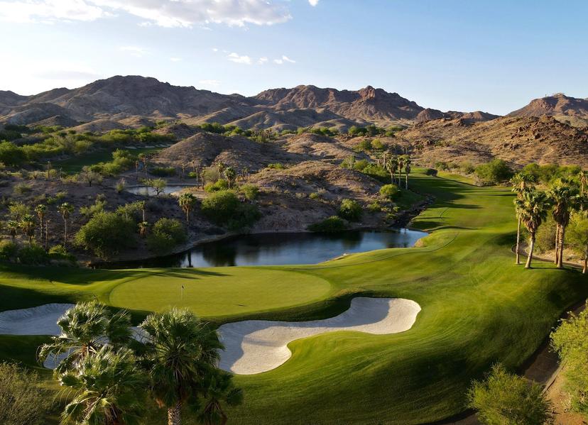 Close-up of a golf green surrounded by sand traps and a tranquil pond.