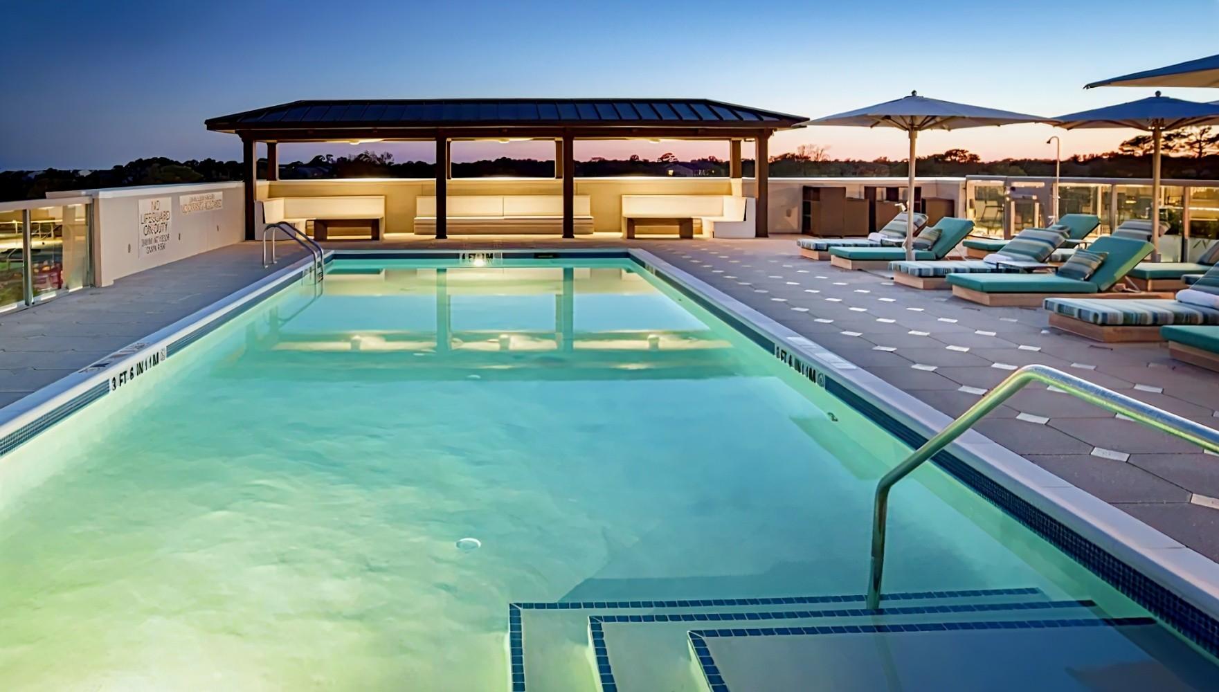 Swimming pool at the hotel with blue sunbeds and a sofa section