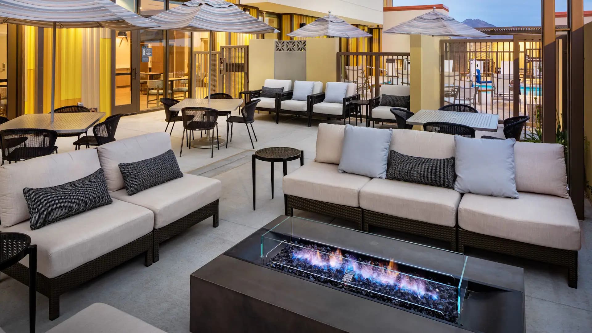 Fire pit places in the centre of an outdoor seating area with tables and sofas available