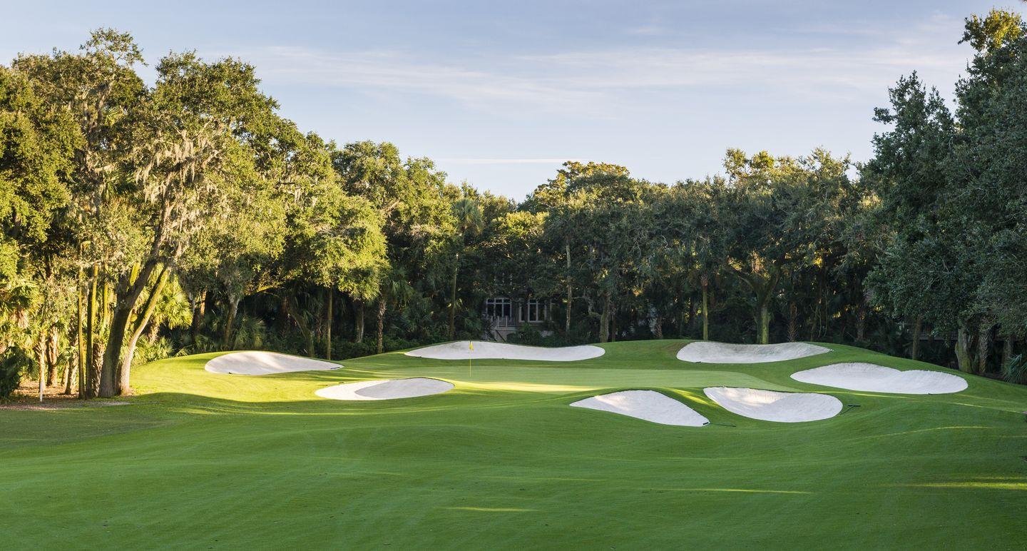 Manicured green surrounded be seven uniquely shaped sand bunkers
