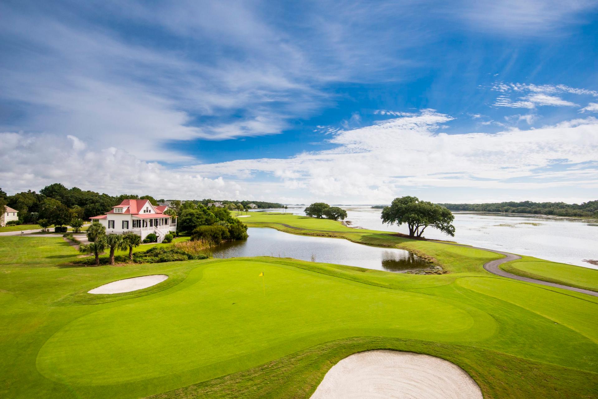 Well-maintained green sandwiched between two bunkers under blue skies with coastal views