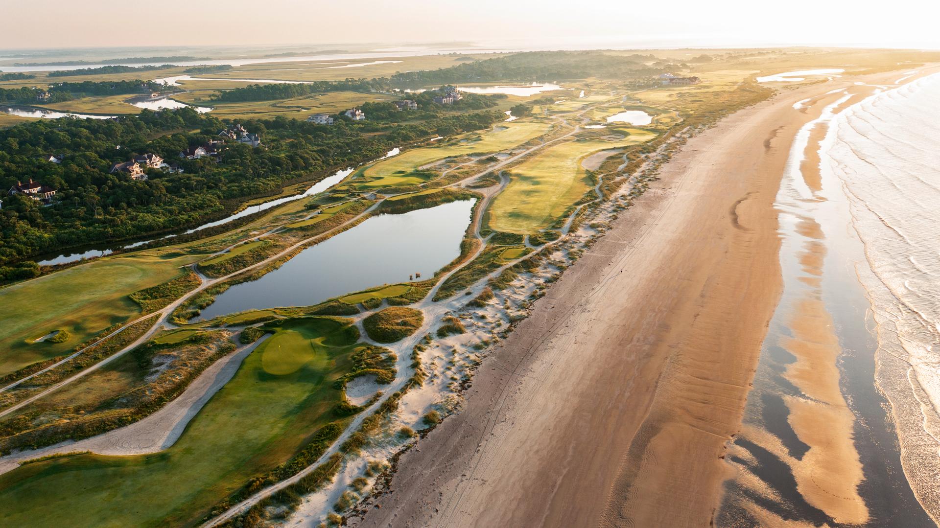 An aerial view of the ocean course, featuring lush greens and winding waterways by the beach.