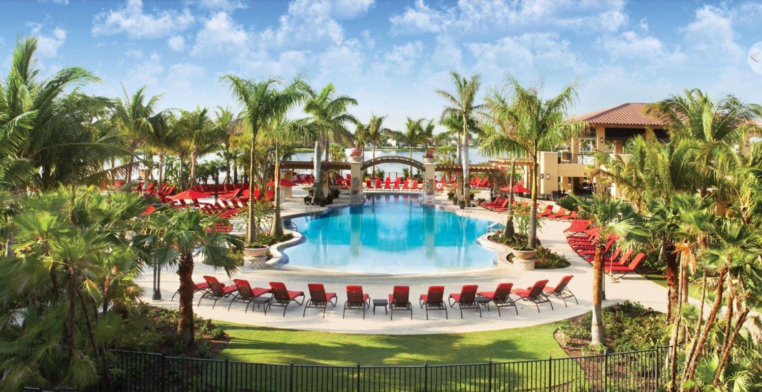 Panoramic view of a swimming pool at the PGA National Resort surrounded by red sun beds