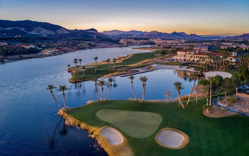Aerial view of a world-class golf course with smooth greens and serene waterfront scenery.