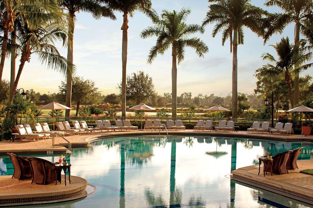 Outdoor swimming pool at The Ritz Carlton Naples surrounded by sunbeds and palm trees