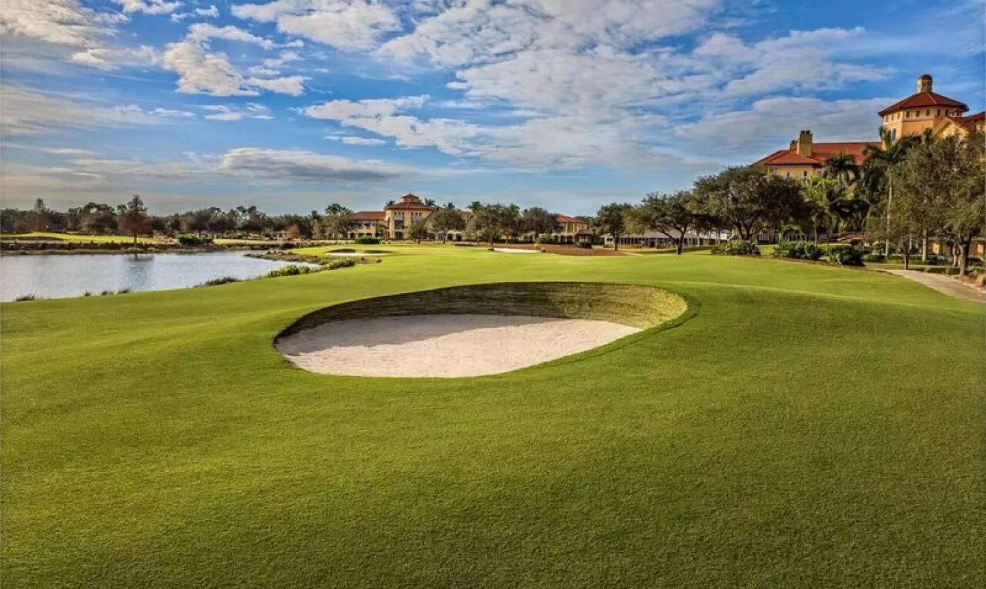Deep sand bunker placed on the winding fairway next to a lake that runs through the course