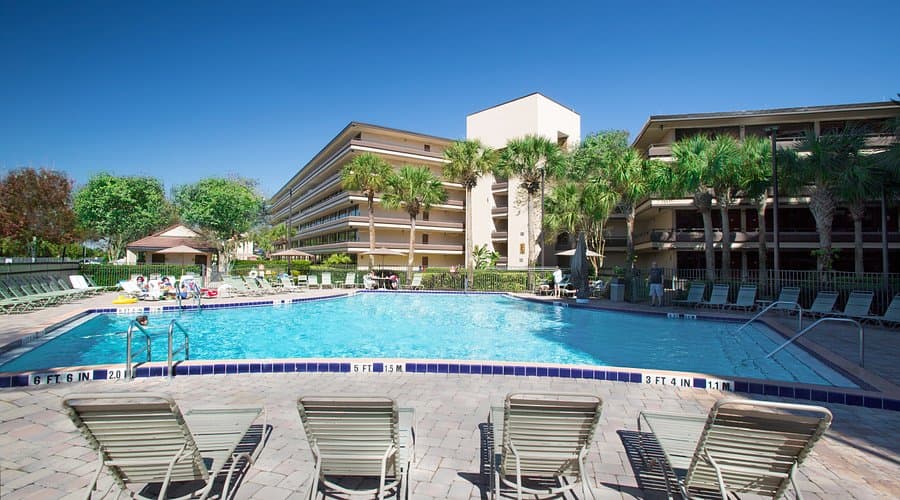 Guest at the Rosen Inn hotel enjoying their day by the pool with the building in the back