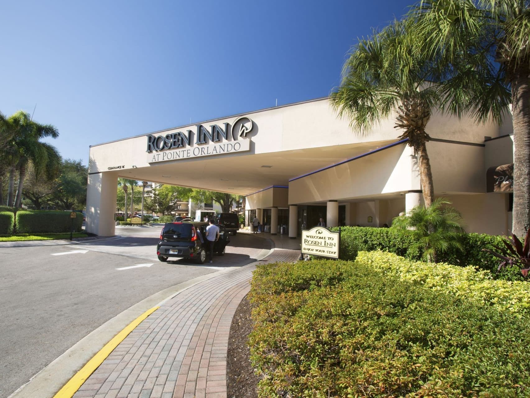 Exterior view of the front entrance to the hotel building with its logo in large writing above the drop off point