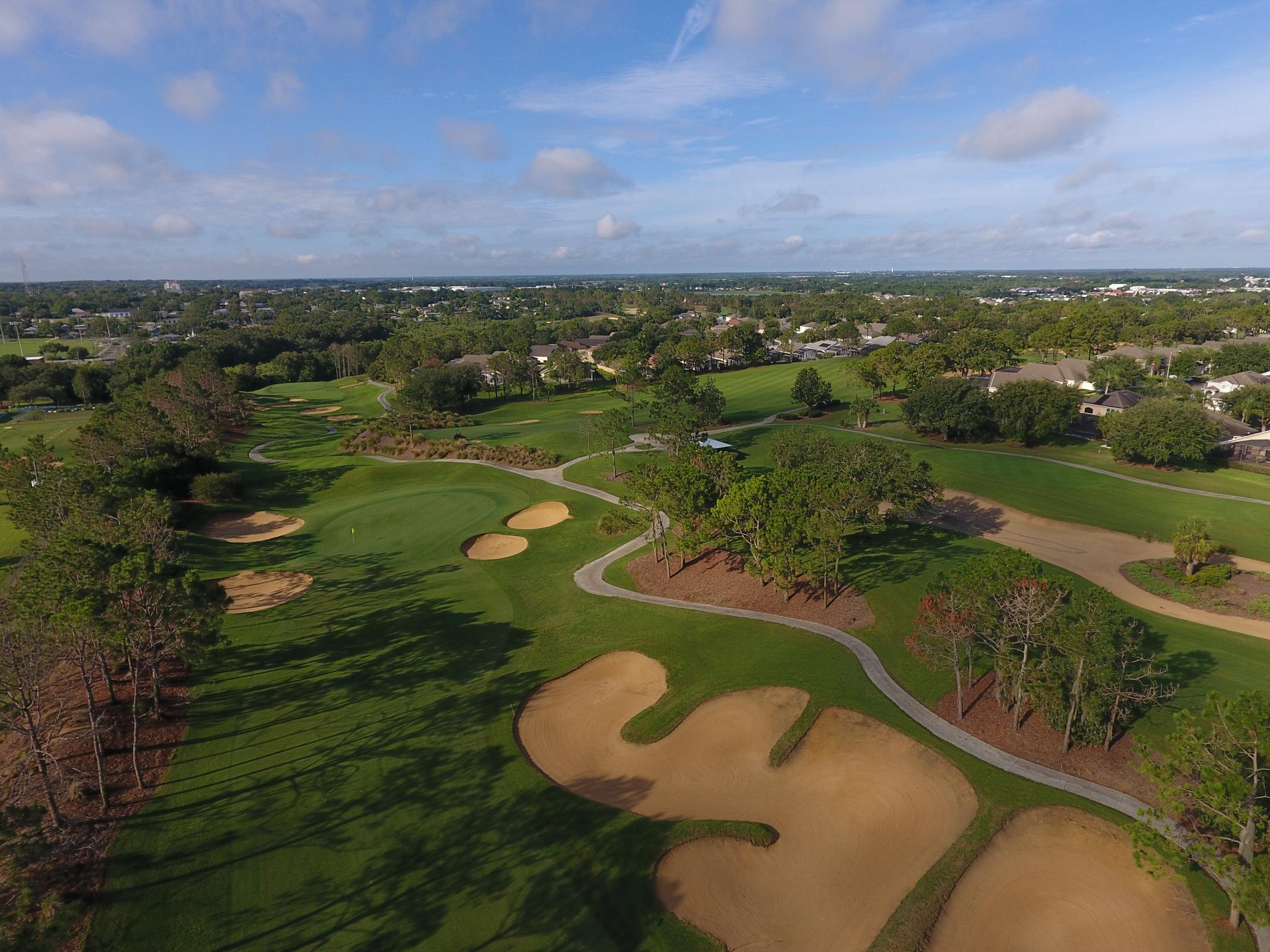 A wide aerial shot of the course, highlighting rolling greens and numerous bunkers surrounded by residential areas.