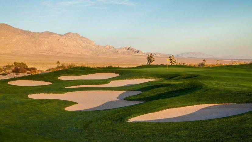 Five uniquely shaped sand bunkers placed next to a smooth green under blue skies