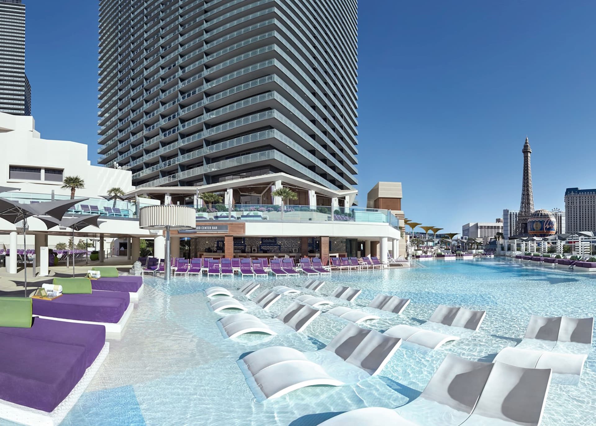 Panoramic view of the hotel building towering over their outdoor swimming pool