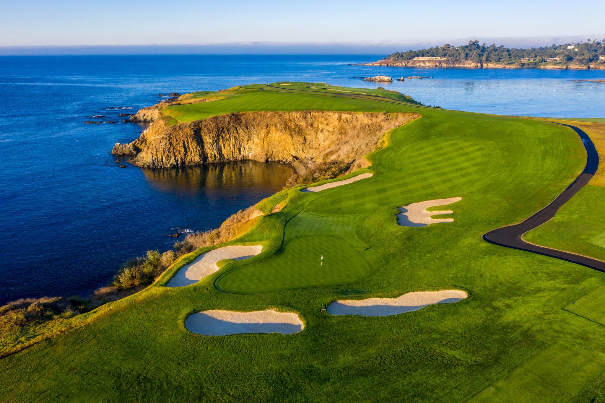 Aerial view the course with a manicured green surrounded by uniquely shaped bunkers