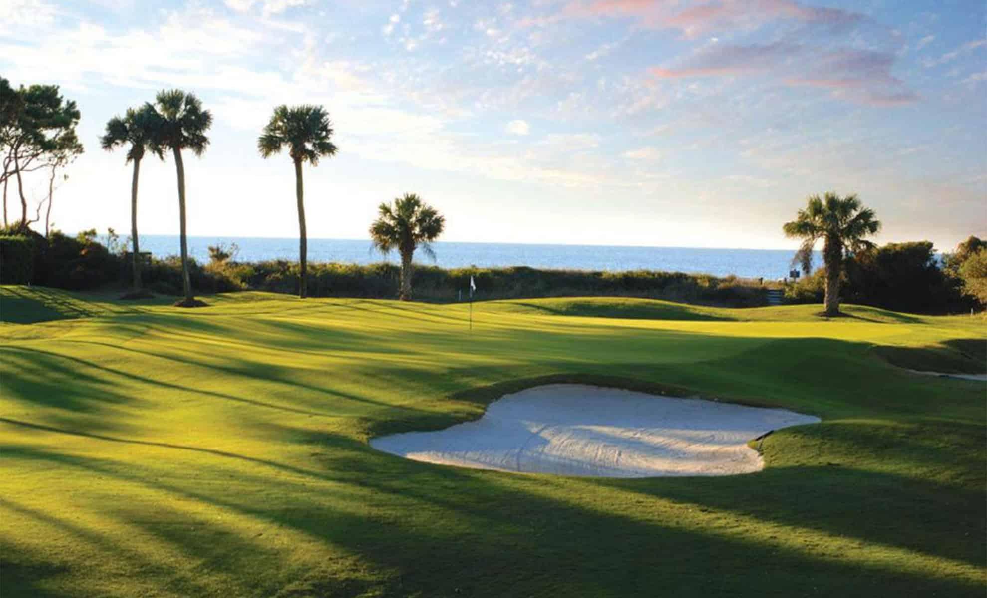 Smooth green with a strategically placed bunker just next to it and sea views