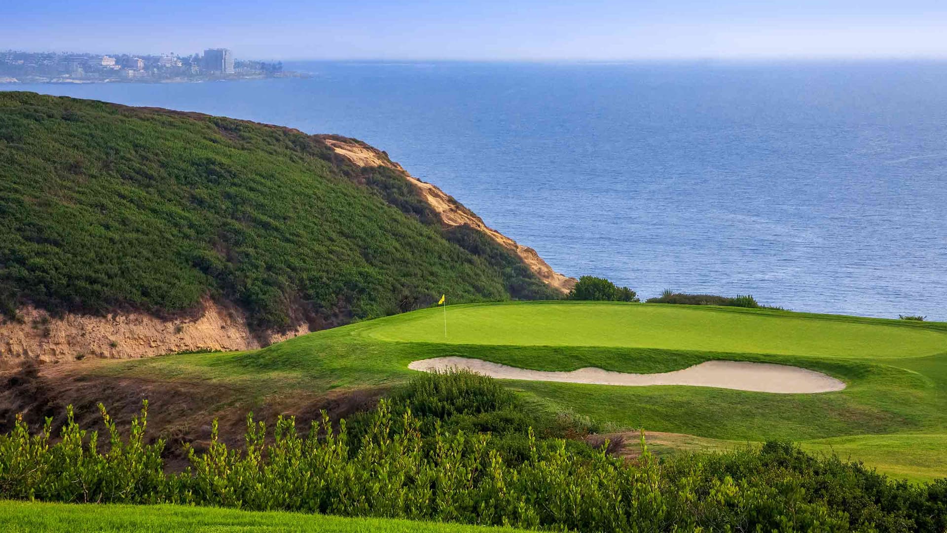 A smooth green strategically placed at the edge of the course with a sand bunker nestled just next to the green