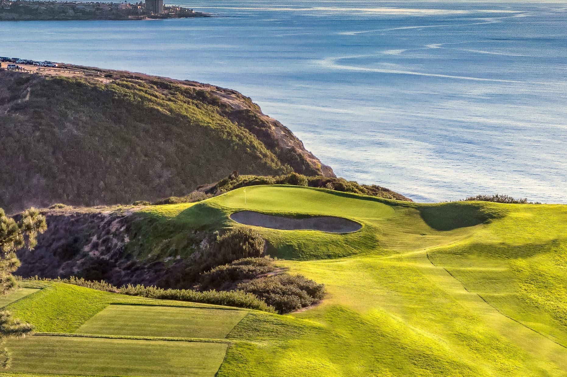 A green strategically placed at the edge of the course with a sand bunker nestled just next to the green and sea views