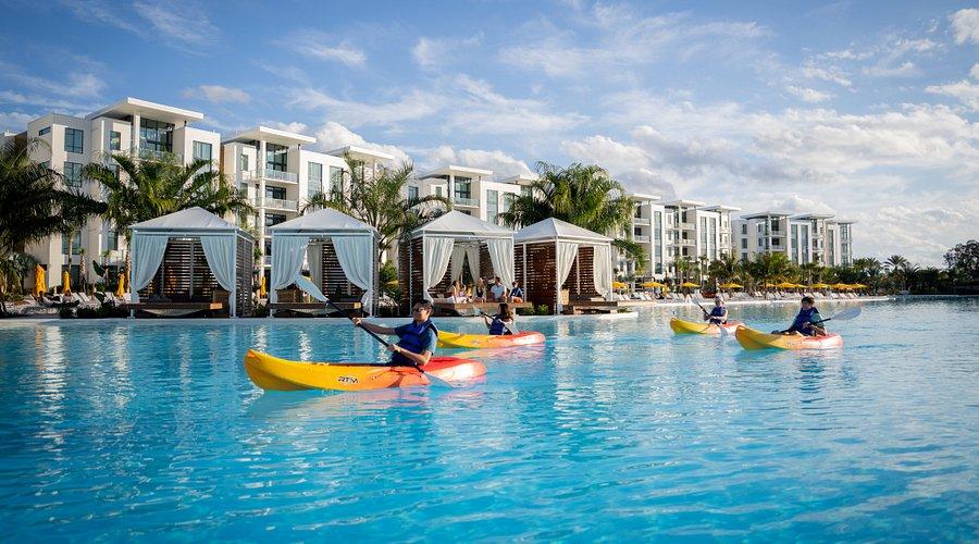 Guests enjoying a canoeing experience on the 8-acres of swimming pool at the hotel with cabanas in the back