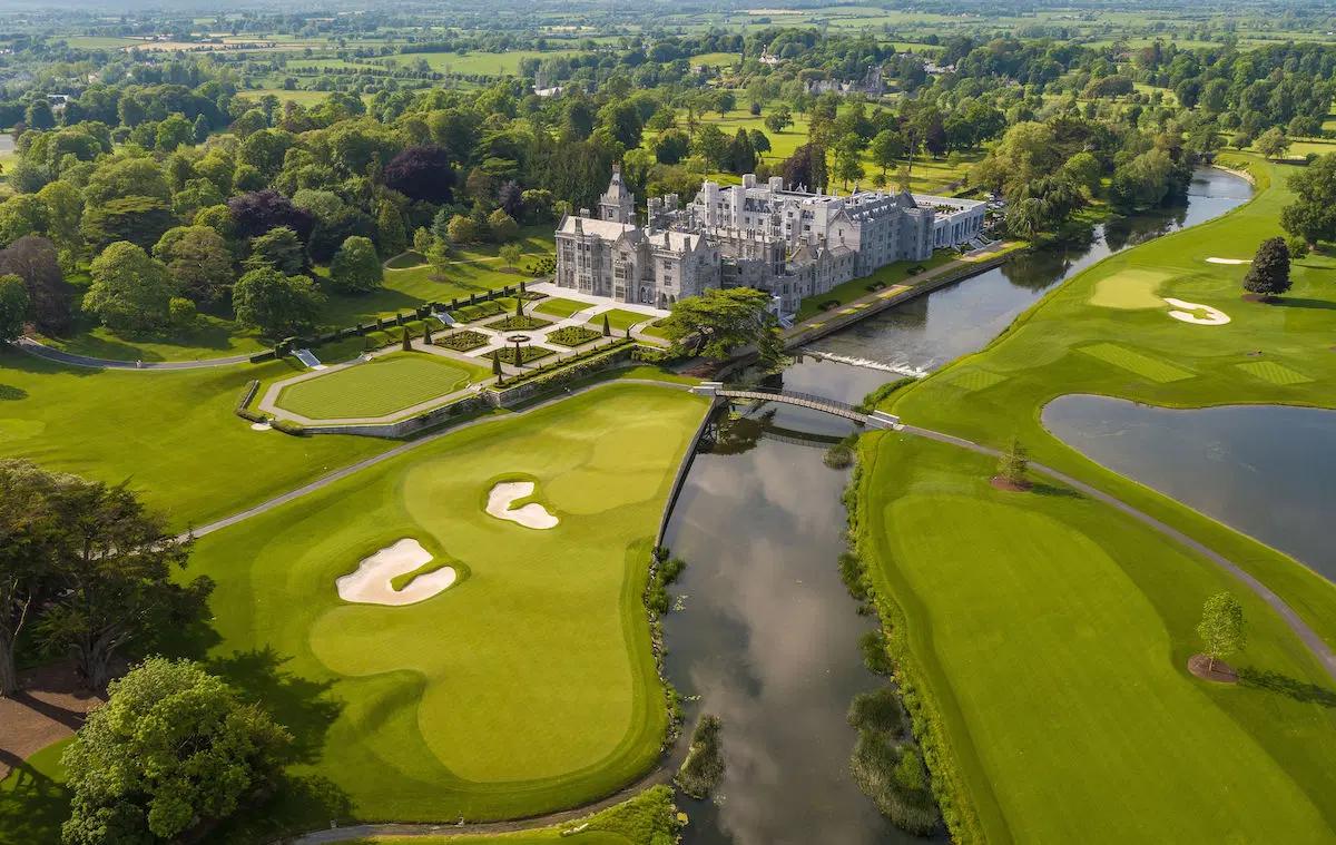 Aerial view of Adare Manor surrounded by a lush golf course and river.