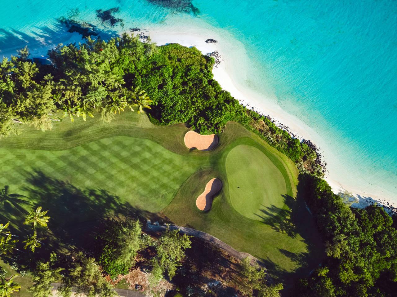 Birdseye view of a wide fairway leading to a smooth green nestled with two sand bunkers