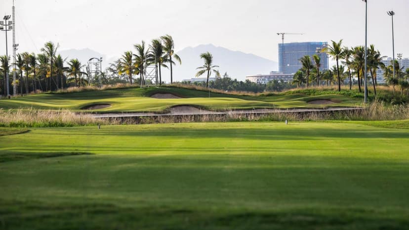 A smooth green nestled with sand bunkers and city views in the distance