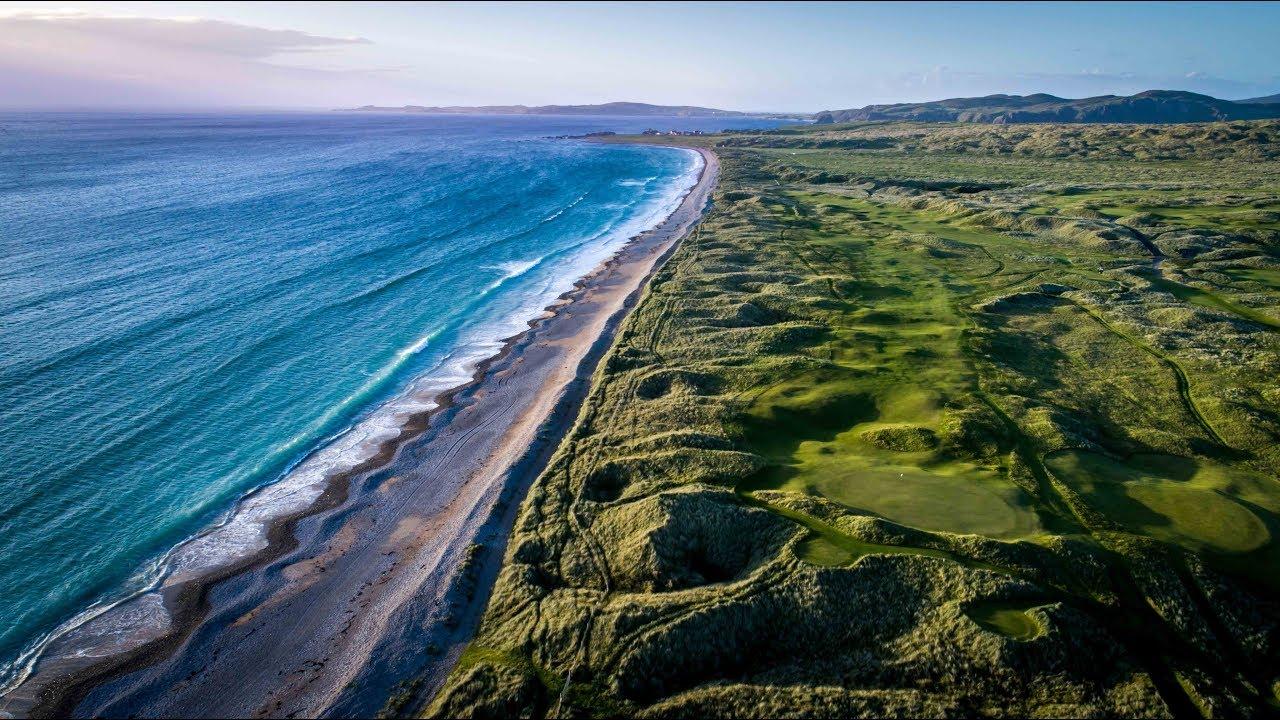 Aerial shot of the course showcasing its manicured greens and a lovely view of the beach and sky blue water