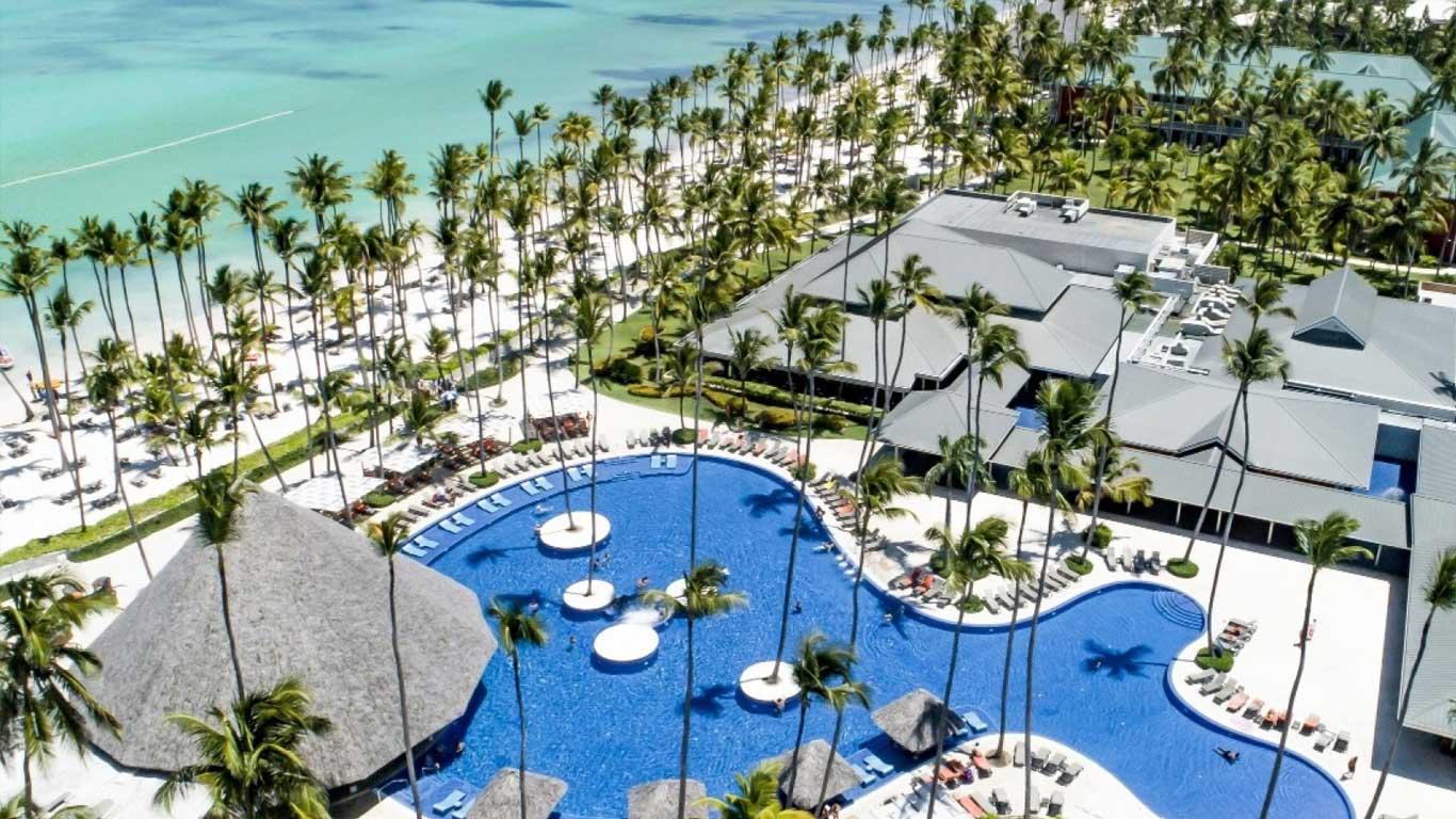 Aerial view of the resorts swimming pool leading to the beach both littered with palm trees