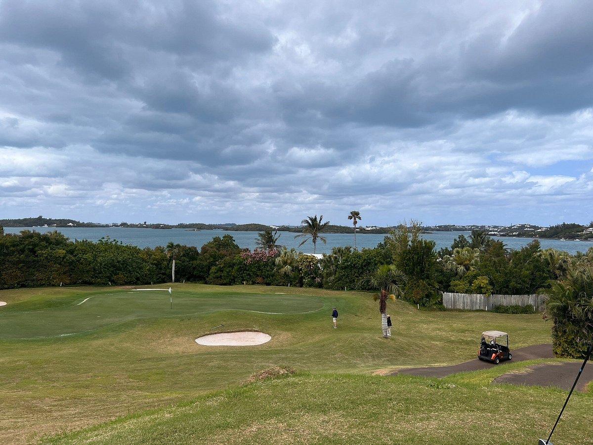 A scenic green overlooking the ocean with a golf cart path winding through the landscape.