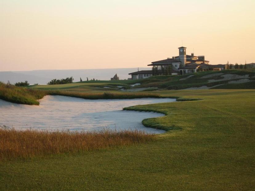 A large sand bunker placed on a well-maintained fairway leading towards the resort building
