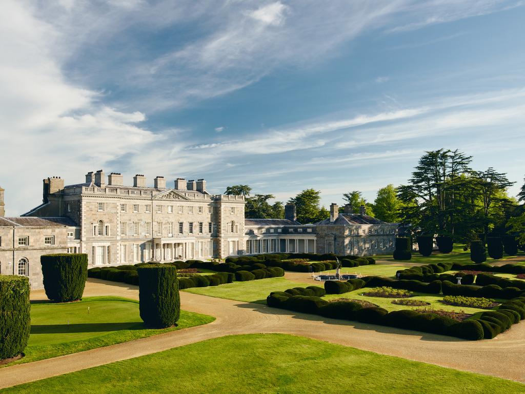 A panoramic view of a historic manor with formal gardens and pathways.