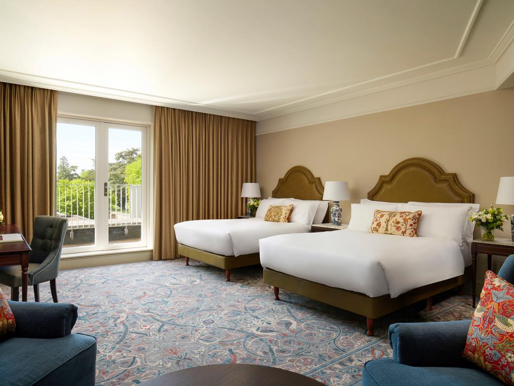 A spacious hotel room with two double beds and a private balcony view.