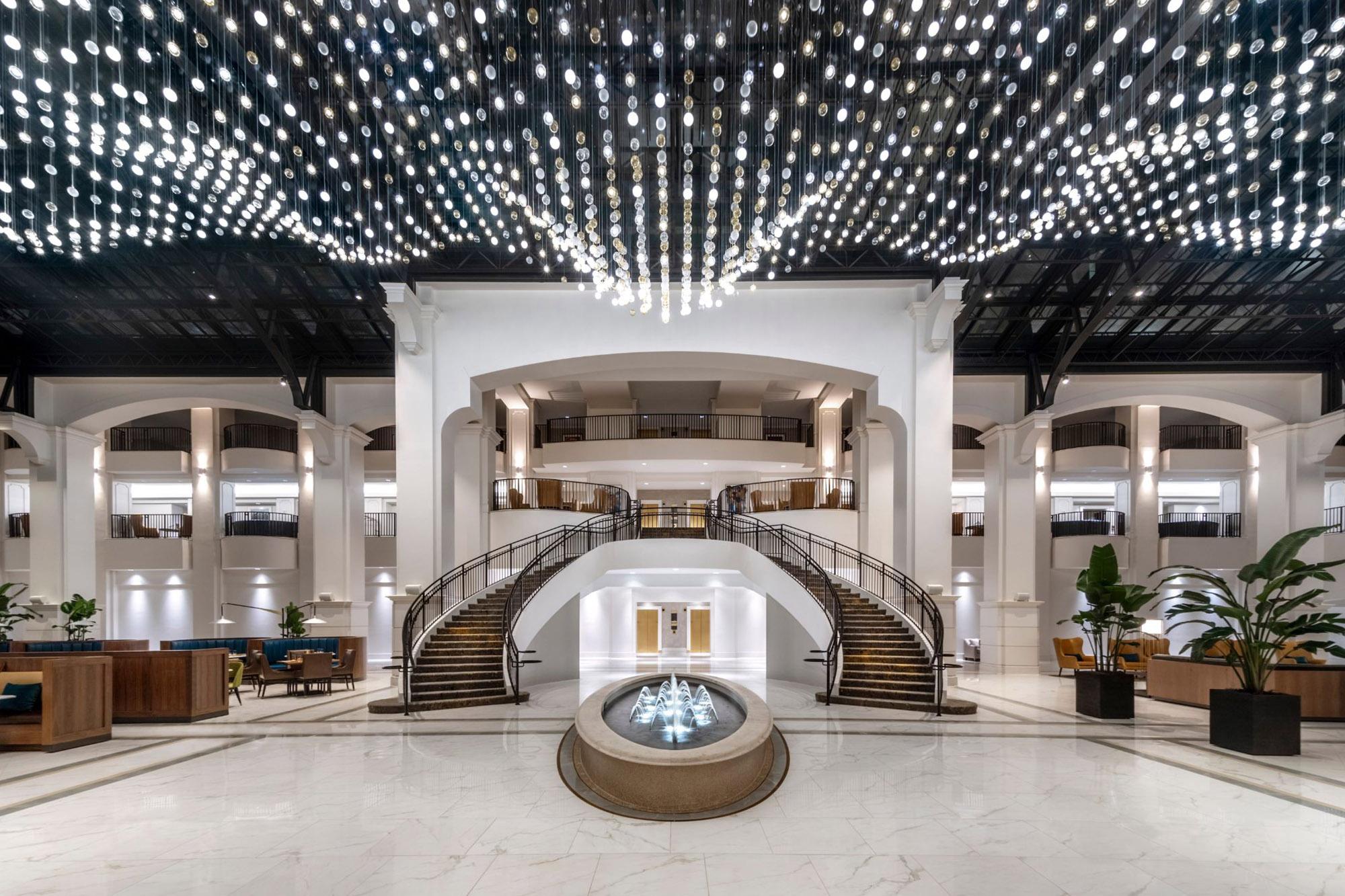 A stunning interior view showcases a sweeping staircase and dramatic ceiling lights in the luxurious hotel lobby.