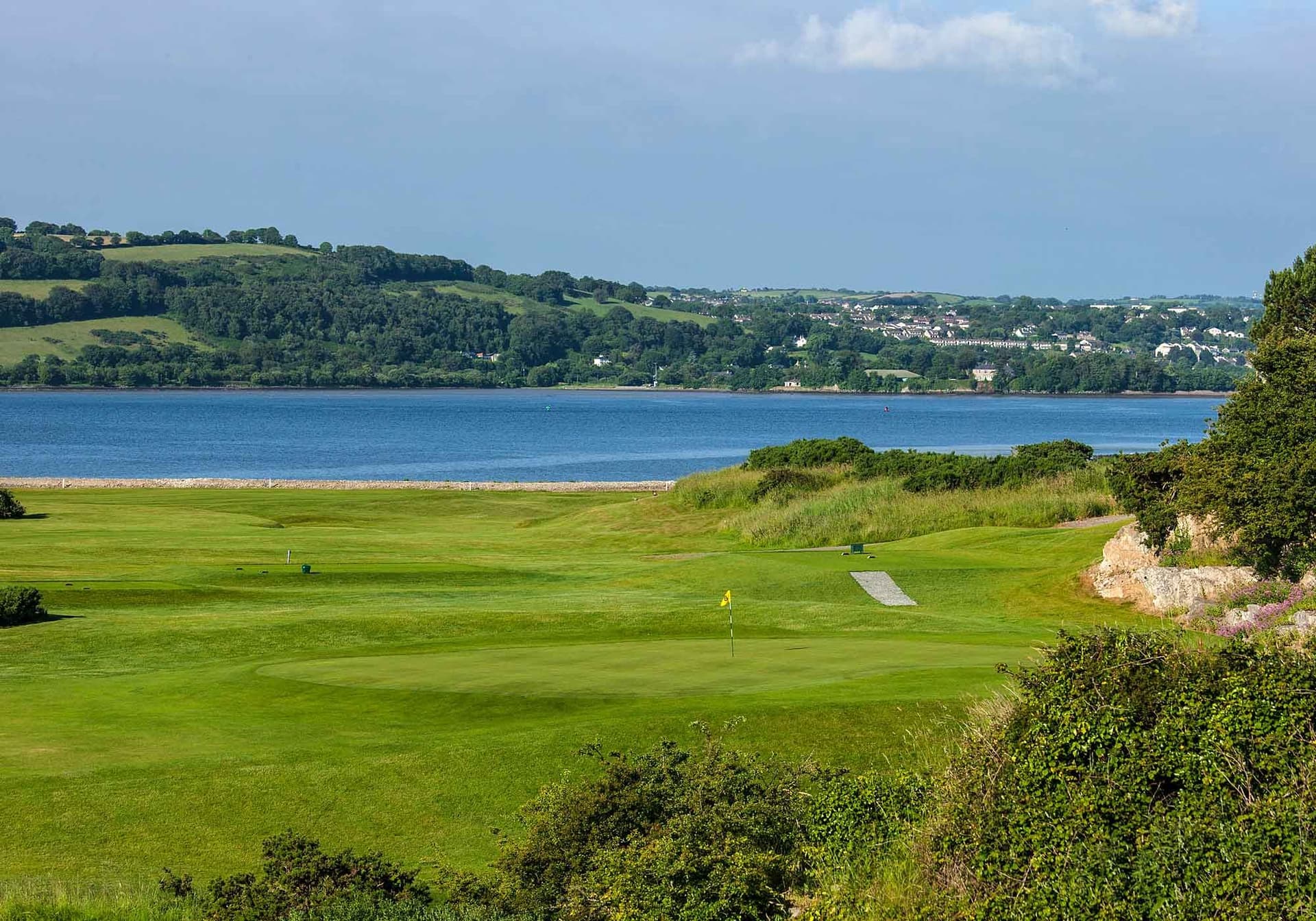 A green overlooking the water with sweeping views of the surrounding hills and villages.