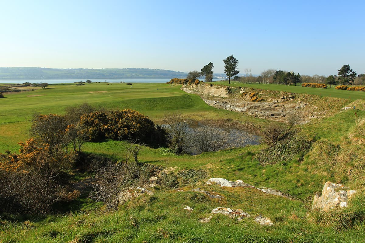 A scenic fairway running along rugged limestone quarry edges with coastal views in the distance.