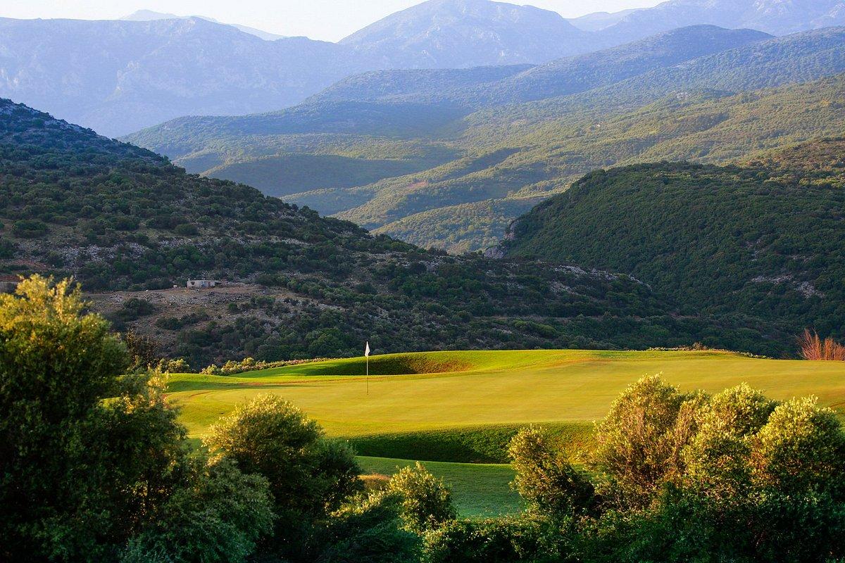 A secluded green sits surrounded by lush hills
