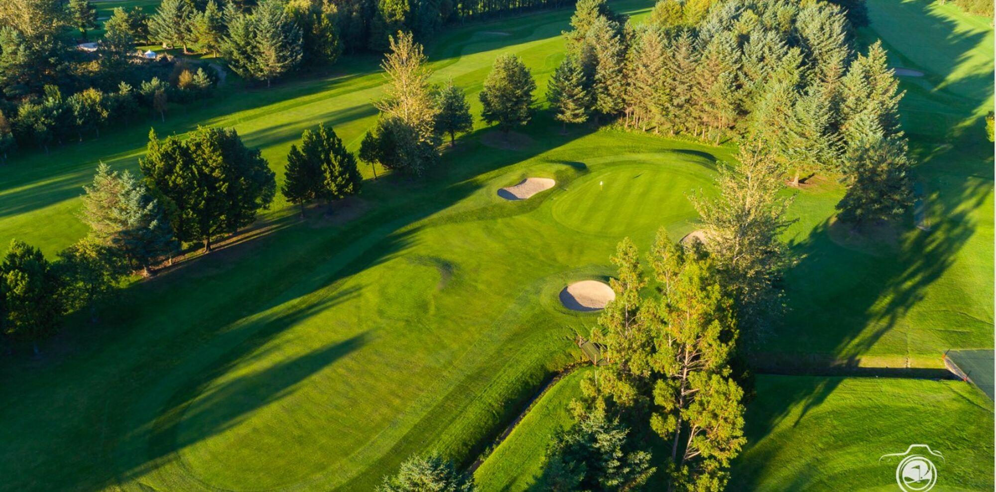 A sweeping aerial view of Deerpark’s lush fairways and greens bordered by mature trees.