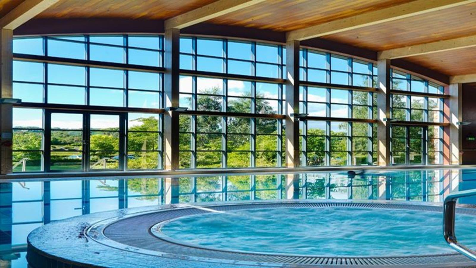 Indoor spa with large windows and serene pool area.