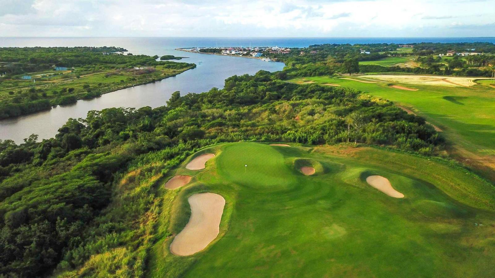 A smooth green surrounded by sand bunkers with sea views