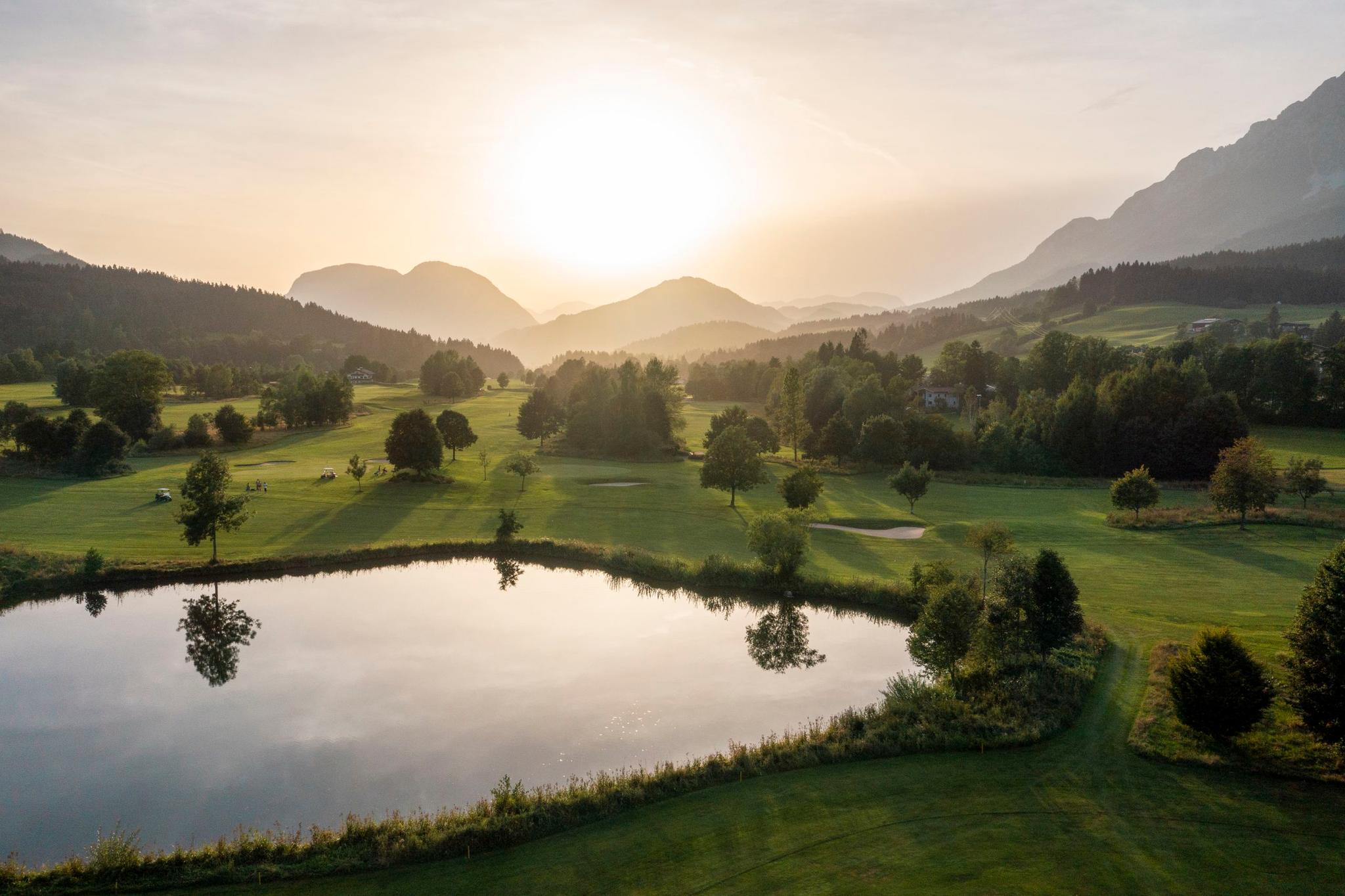 Sun setting over the Elmau Gold course with a large water feature in the centre