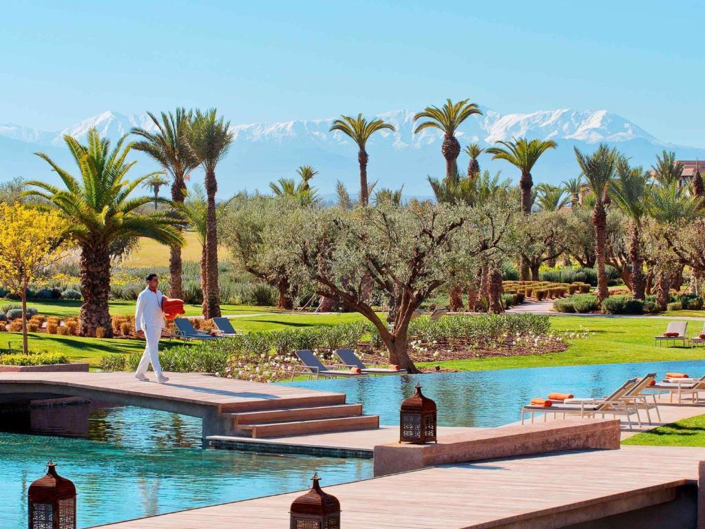 Outdoor swimming pool surrounded by palm trees with a bridge to navigate the hotel