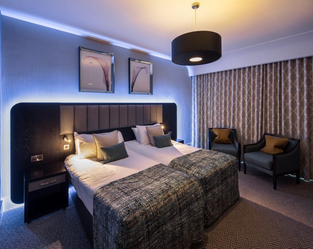 Modern twin hotel room with cozy lighting and elegant decor.