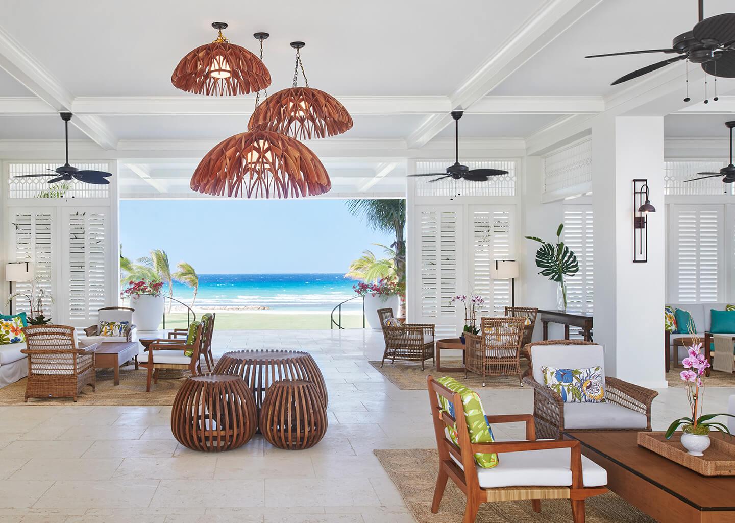 Reception at the hotel with different seating options and a staircase leading down onto the beach