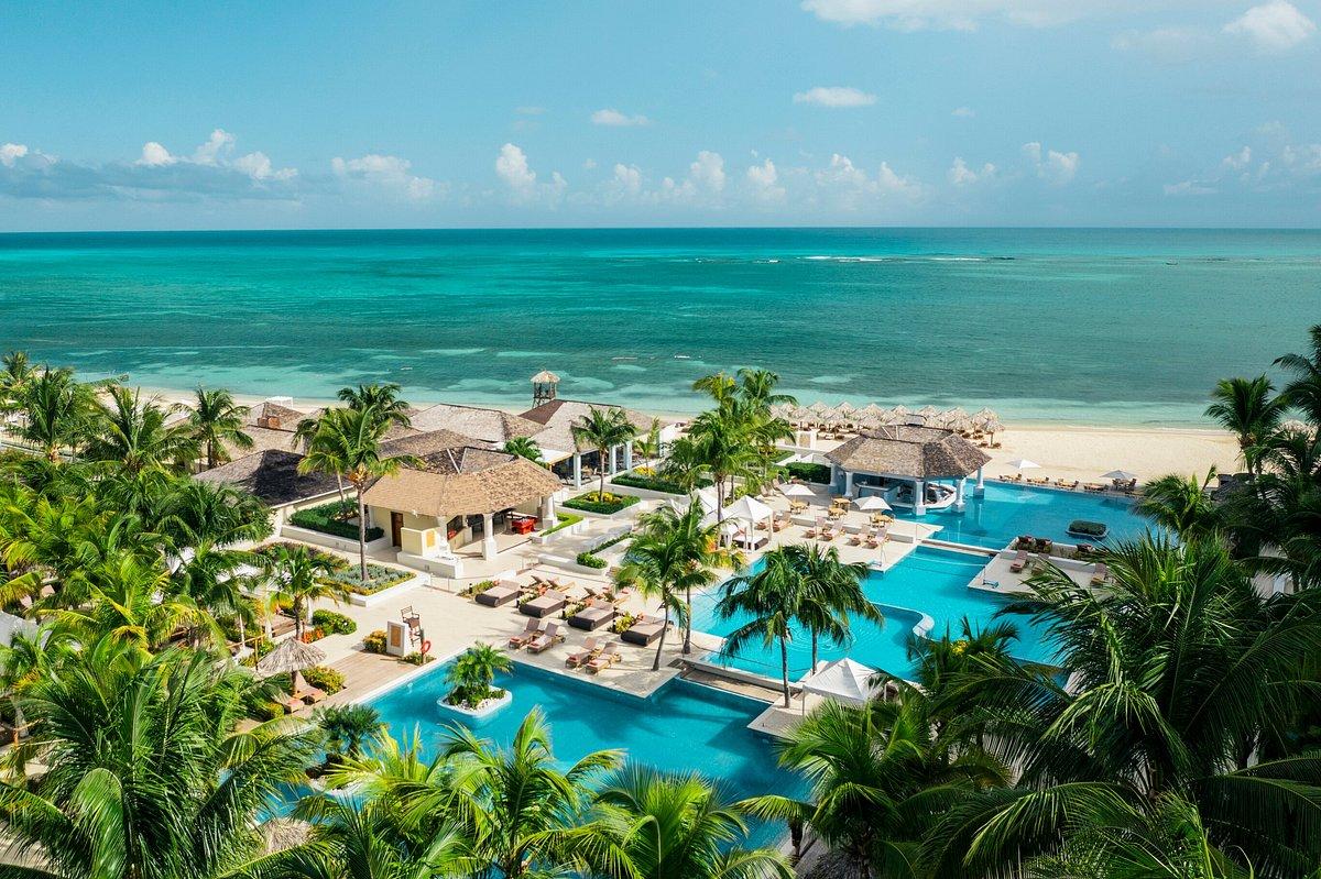 3 separated swimming pools at the hotel surrounded by palm trees with coastal views