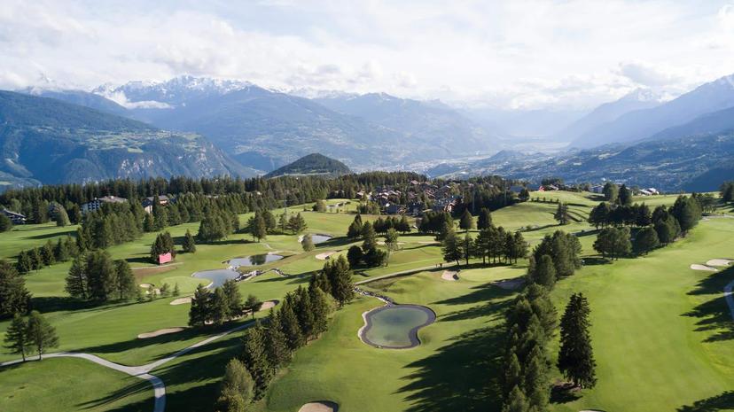 Overhead view of the Golf Club de Crans Sur Sierre with ice top mountains in the distance