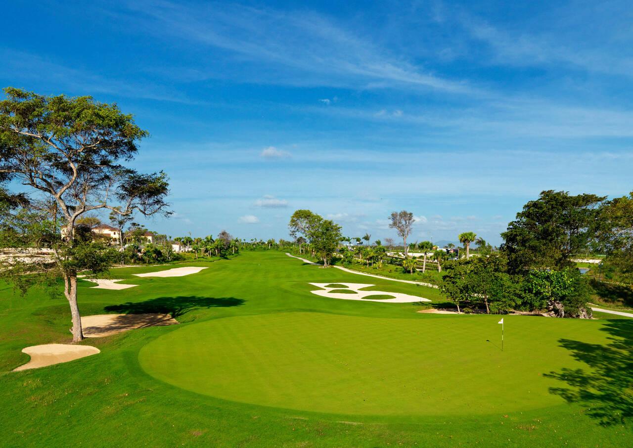 A wide well-maintained fairway nestled with sand bunkers leading to a smooth green