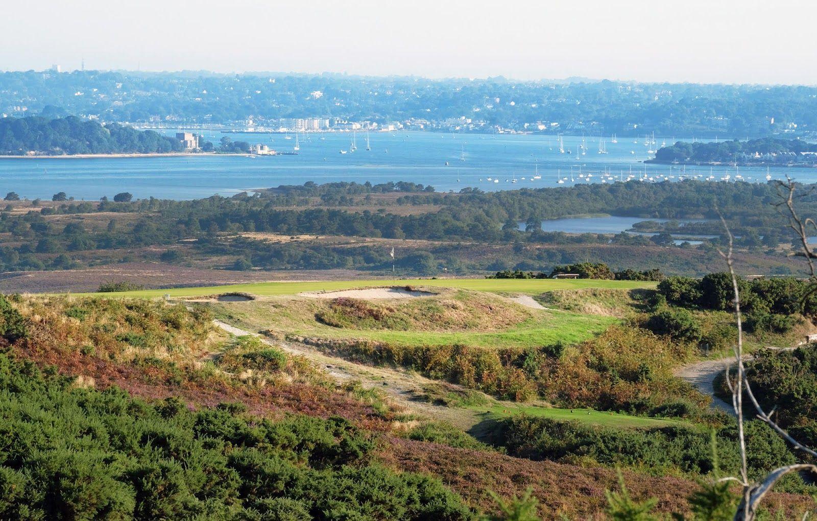 Smooth green placed on elevated surface with a strategically placed bunker with a boat dock in the distance