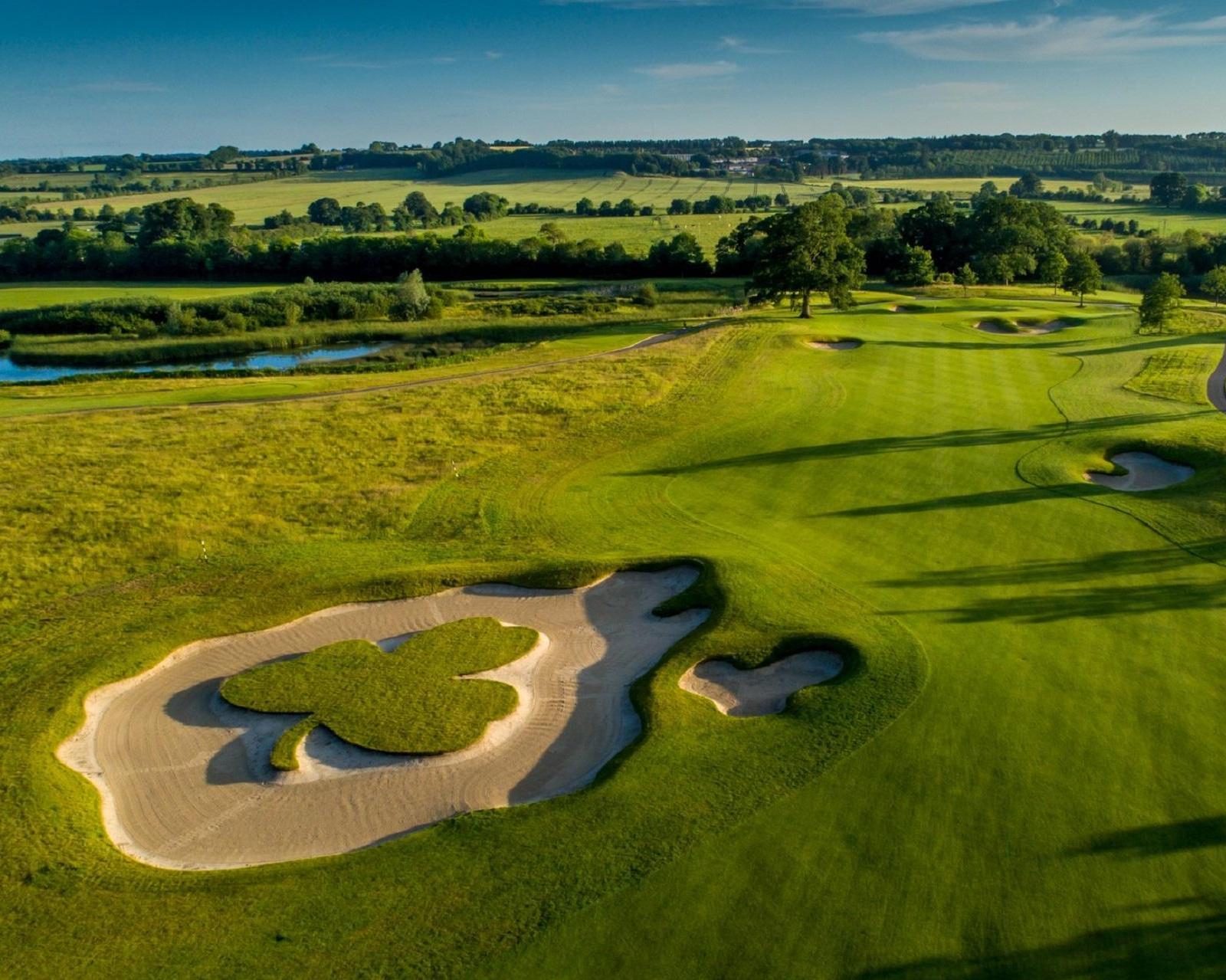 A shamrock-shaped bunker sits on a scenic golf course.