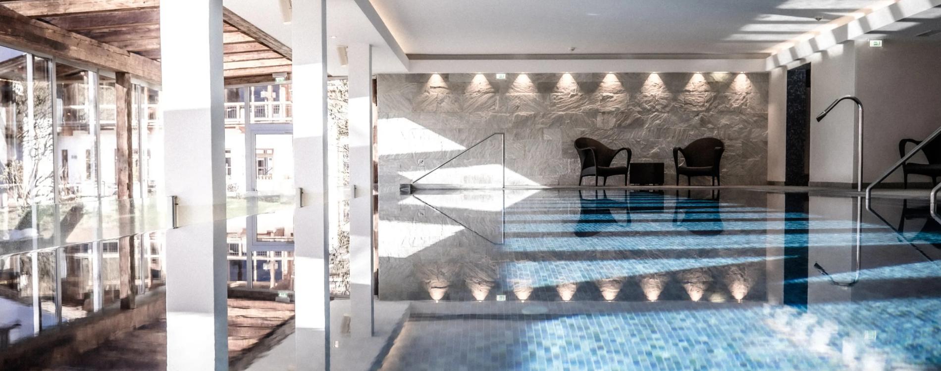 Indoor swimming pool at the hotel featuring poolside chairs and a panoramic window