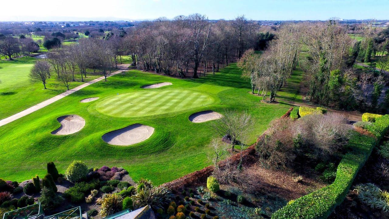 A perfectly manicured green surrounded by sand traps, nestled among trees and lush landscaping.