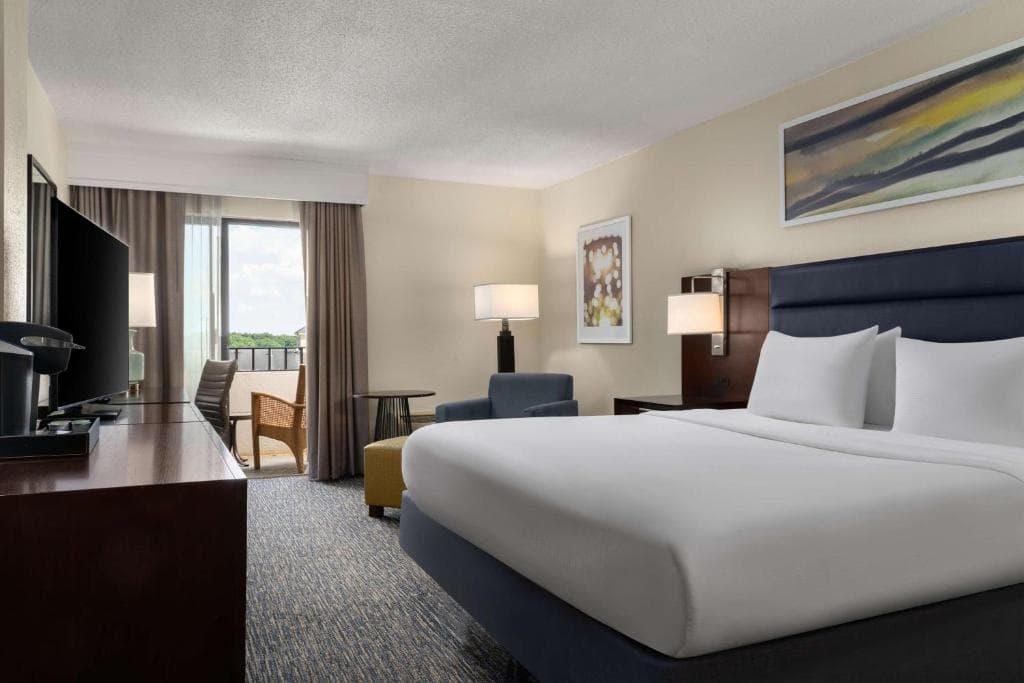 A Marriott Columbia hotel double bedroom with a large bed, TV, and balcony view.