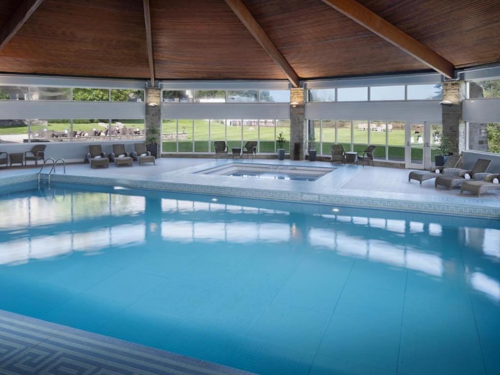 An indoor swimming pool with large windows overlooking outdoor scenery.